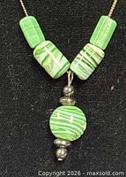 Necklace pendant detail showing green glass beads and silver spacers
