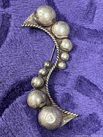Front view of silver brooch showing graduated beads and curved shape