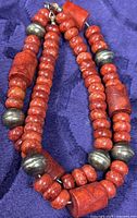 Necklace coiled showing coral rondelle and cylindrical beads with silver pearls and clasp