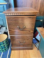 front view of medium brown two-drawer oak veneer filing cabinet with brass-tone handles
