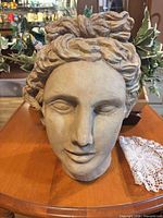 Front view of terracotta head planter showing facial detail and patina