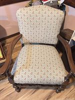 Front view showing floral upholstery, wood arms, carved legs