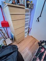 Wood dresser adjacent to plastic drawer tower, room context