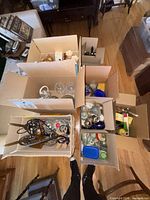 Top view of multiple boxes showing variety of glassware, jars, plastic containers and decor items