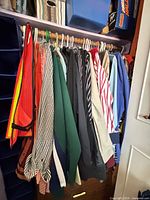 Closet rod with multiple shirts, jackets, safety vests and sweaters on hangers