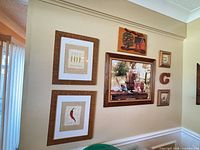 Group of framed prints on wall showing vegetable prints, still life, wood sign and small framed pieces