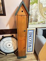 Front view of tall birdhouse cabinet showing wood body, green roof and base