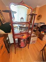 Full front view of mahogany étagère showing mirrored back, shelves and cabinet