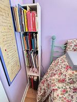Full view of one tall narrow white bookcase filled with children’s books
