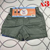 Front view of green shorts with packaging card attached, blue pair partially visible beneath