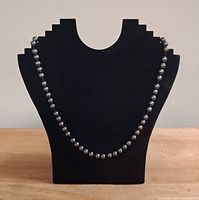 Necklace displayed on stand showing full drape