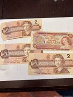 Front sides of four Canadian $2 banknotes displaying portraits and denominations