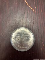Reverse of sealed 1976 $10 Montréal Olympics coin showing globe design and denomination
