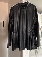 Full front view of black pleather coat on hanger showing zip closure, long sleeves, stand collar