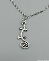 Close-up of silver-tone gecko pendant on chain