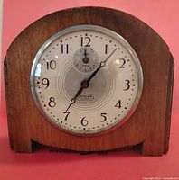 Front view showing wood case, dial, bezel, numerals and alarm sub-dial