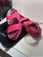 Top view of both pink platform sandals resting on black John Fluevog dust bag