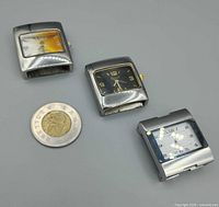 Front view of three watch heads beside Canadian loonie for scale