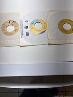 Three 7" singles in sleeves laid side by side