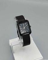 Front view of black rectangular quartz watch on stand