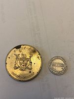 Ontario coat of arms side of Expo ’70 medal beside TTC subway token for scale