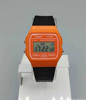 Front view showing orange case, digital display, black strap
