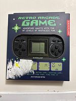 Front of boxed Kikkerland Pocket Retro Arcade Game showing screen and controls