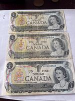 Front view of three 1973 Canadian $1 notes, serial numbers visible