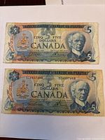 Fronts of both $5 bills showing portraits, denomination, serial numbers