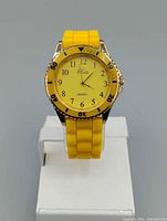 Front view of yellow quartz wristwatch on stand