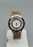 Front view of rose gold watch on stand showing dial and bezel