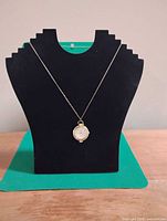 Pendant watch hanging on display bust showing overall appearance and chain length