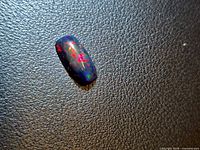 Full view of the Ethiopian black opal showing multicolored play-of-color on dark body