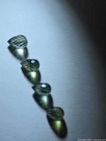 Four green briolette-cut sapphires under light