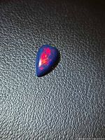 Pear-shape black opal showing red flash on dark body