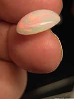Side profile of oval cabochon opal showing curvature and color play