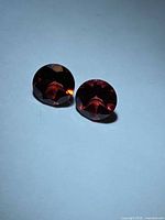 Two round bright red garnets side by side on neutral background