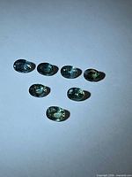 All seven oval green sapphires grouped on white background