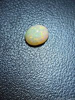 Top view of oval cabochon opal showing pinfire play-of-colour