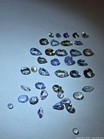 Entire group of approx 30 faceted Tanzanite stones on white background