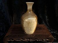 Front view of stoneware vase with earth-tone glaze and leaf motif