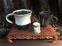 Front view of all three pottery vessels on wooden stand