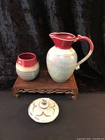 Pitcher, cup and lantern lid displayed on wooden stand