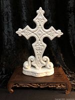 Front view of white glazed ceramic cross on scroll base