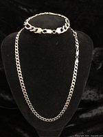 Necklace and bracelet displayed on black bust form