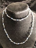 Necklace draped on bust form showing bead spacing and silver wire links