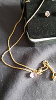 Chain necklace and pendant with amethyst stone beside earrings box