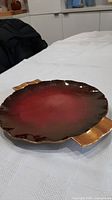 Top view showing full dish, red glaze, fluted rim, gold handles