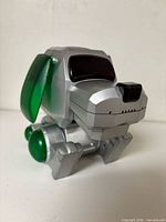 Front angled view of silver robotic dog with green ears and joints
