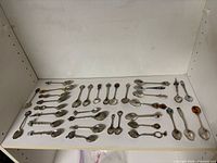 Full layout of 33 assorted souvenir spoons on shelf